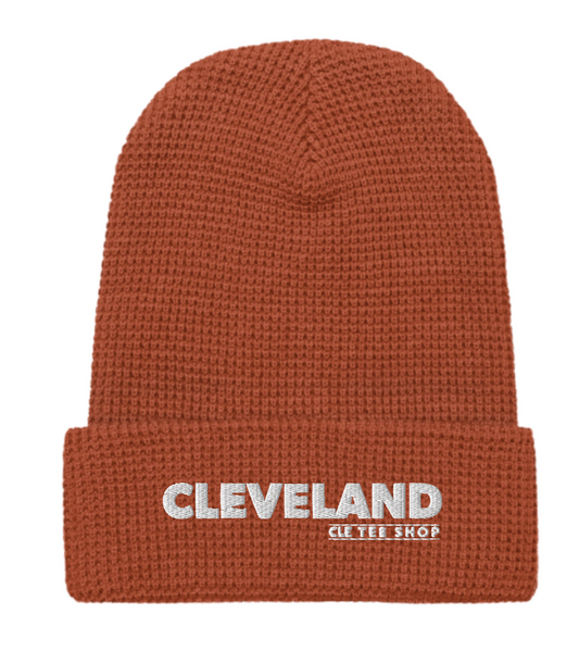 Rust orange beanie with bold 'Cleveland' and 'CLE TEE SHOP' text on bottom cuff